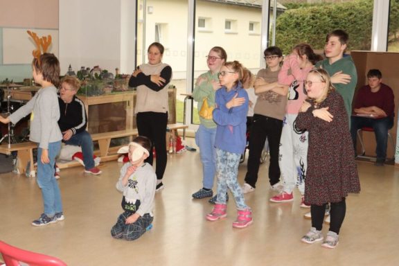 Gruppenszene mit Kindern und Erwachsenen, die gemeinsam aktiv an einer Aufführung teilnehmen.