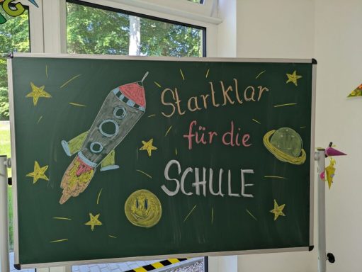 Eine Tafel mit einem bunten Raketenmotiv und der Aufschrift "Startklar für die Schule".