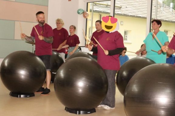 Gruppentherapie mit Menschen, die auf großen Bällen Trommeln und Spaß haben.
