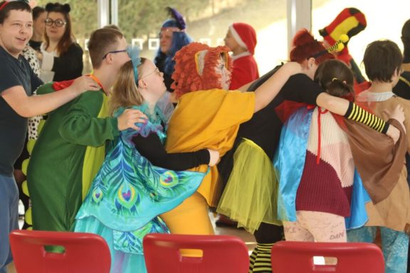 Gruppenszenen mit verkleideten Personen in bunten Kostümen bei einer Feier.