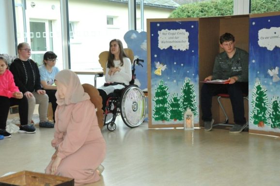 Eine Gruppe von Menschen in einem Raum, während eine Person auf dem Boden spielt.