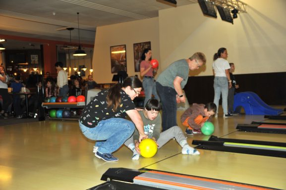 Kinder spielen Bowling in einer lebhaften Bowlingbahn mit bunten Kugeln.