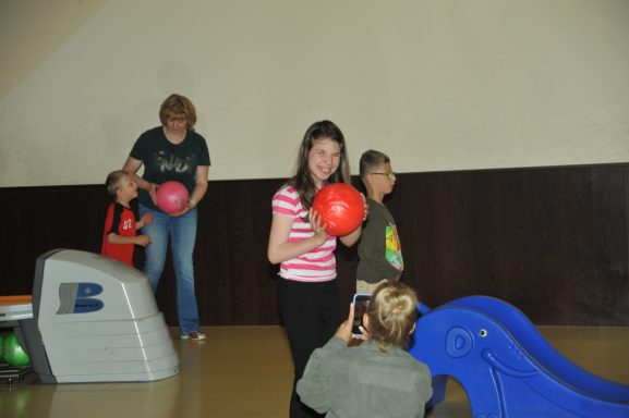 Kinder spielen mit Bällen, während ein Mädchen ein Foto macht. Im Hintergrund eine Rutsche.