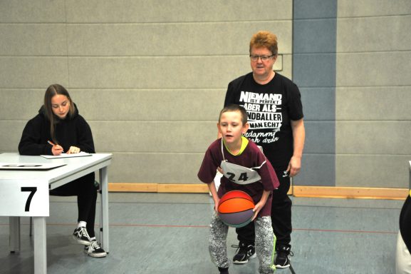 Ein Junge bereitet sich beim Basketballspielen auf einen Wurf vor, während er betreut wird.