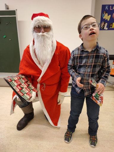 Ein Weihnachtsmann mit einem Jungen, der Geschenke in der Hand hält.