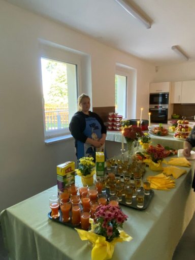 Eine Dame steht an einem festlich gedeckten Tisch mit Getränken und Blumen.