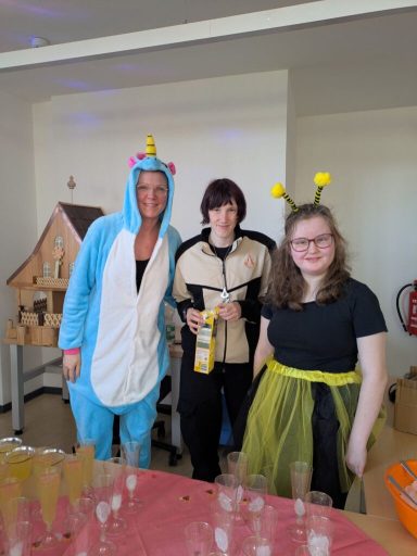 Drei Personen in Kostümen: Ein Einhorn, eine Biene und eine neutral gekleidete Person.