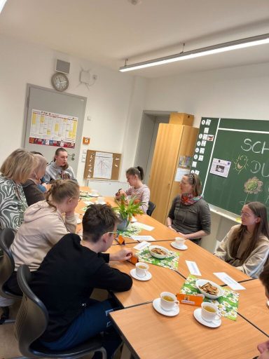Besprechung von mehreren Personen an einem Tisch mit Getränken und Snacks.