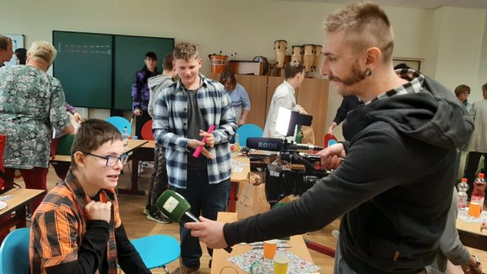 Schülerinterview in einem Klassenzimmer, Lächeln und Austausch im Vordergrund.
