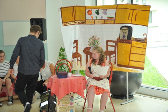 Eine Person sitzt an einem Tisch vor einer großflächigen Küchendekoration.