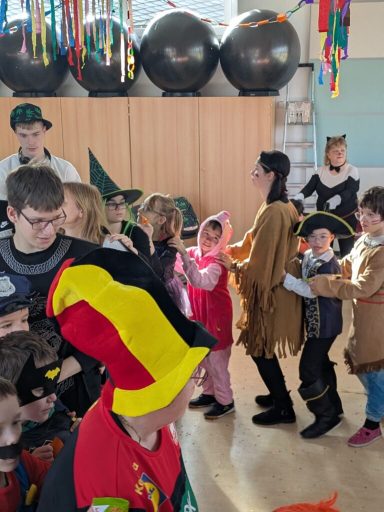 Kinder in Kostümen feiern eine Veranstaltung mit bunten Dekorationen.