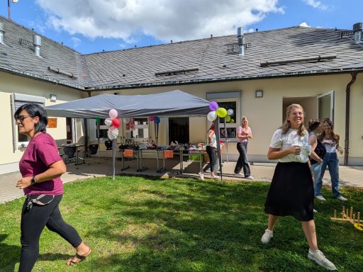 Feier im Freien mit Gästen, Zelten und bunten Ballons in einer Gartenumgebung.