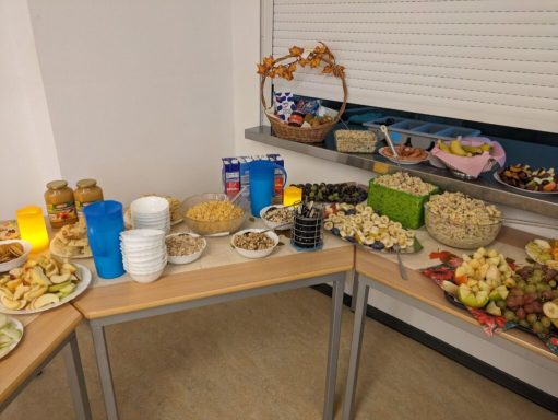 Tisch mit verschiedenen Snacks, Dips und Getränken, umgeben von Dekoration.