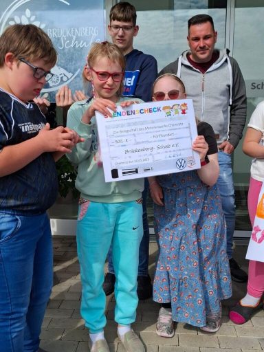 Gruppe von Jugendlichen hält eine Urkunde vor einem Gebäude, lächelnd in den Kamerablick.