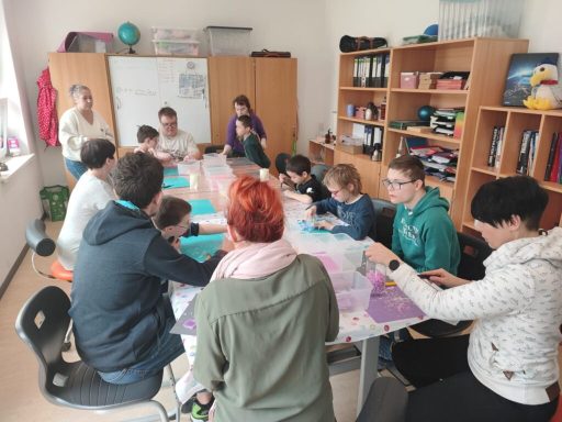 Eine Gruppe von Schülern und Lehrern arbeitet an einem Tisch in einem Klassenzimmer.