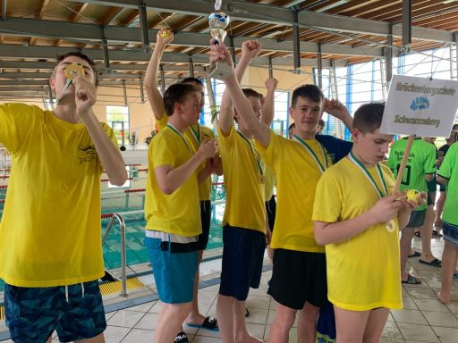 Sechs Jungen in gelben T-Shirts halten Medaillen und feiern am Pool.