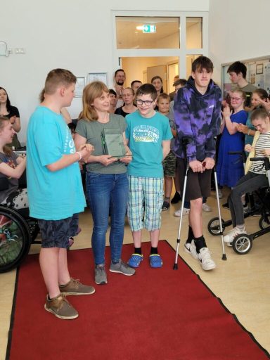 Eine Gruppe von Jugendlichen steht in einem Raum mit Publikum, einige tragen Auszeichnungen.