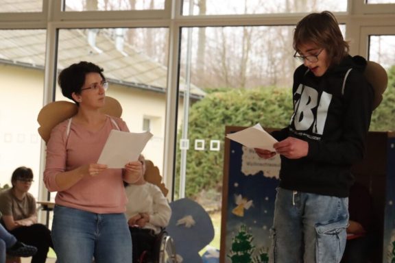 Zwei Jugendliche während einer Aufführung, drinnen, mit Skripten in der Hand.
