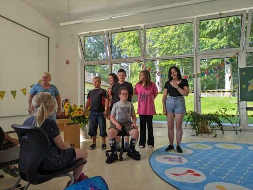 Eine Gruppe von sechs Personen steht in einem Raum mit Fenstern und Pflanzen.