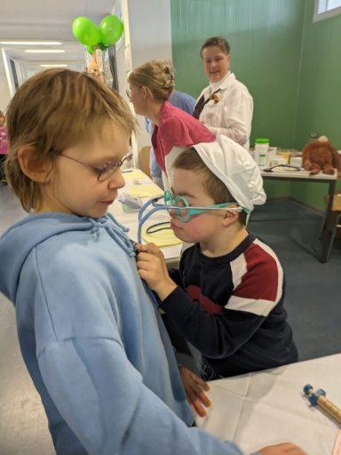 Ein Kind mit Brille untersucht neugierig das Kleidungsstück eines anderen Kindes.