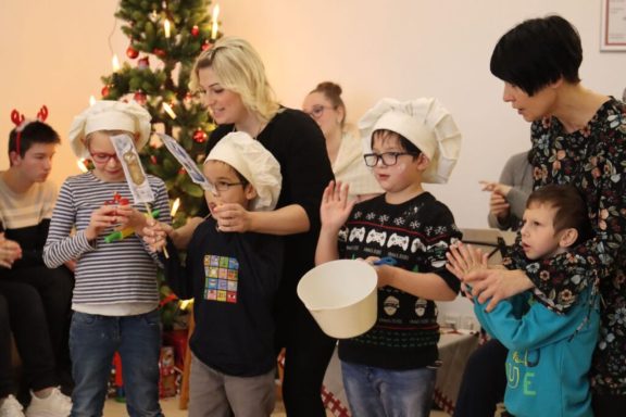 Eine Gruppe von Kindern und Erwachsenen feiert mit Kochmützen und Weihnachtsdeko.