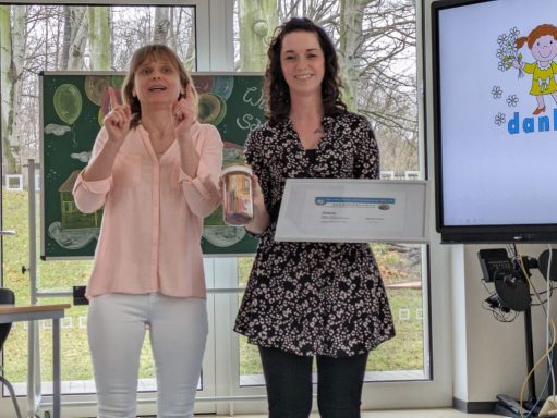 Zwei Frauen stehen zusammen, eine zeigt ein Modell, die andere gestikuliert.