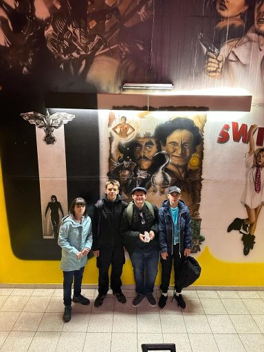 Vier Personen posieren vor Wänden mit bunten Graffiti.