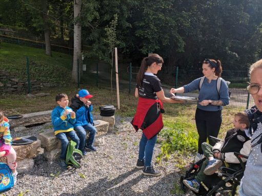 Eine Gruppe von Kindern und Erwachsenen steht im Freien und interagiert miteinander.