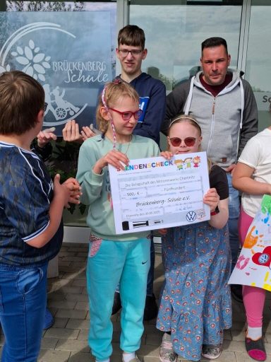 Gruppenszene mit Kindern und Erwachsenen, die eine Urkunde stolz halten.