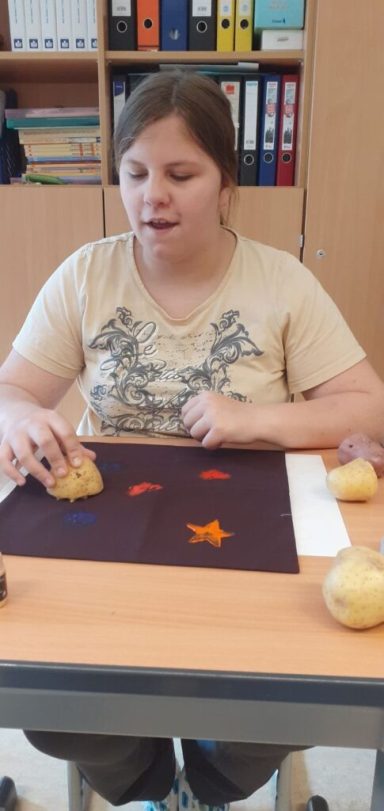 Eine junge Frau arbeitet an einem Tisch mit bunten Formen aus Knetmasse.