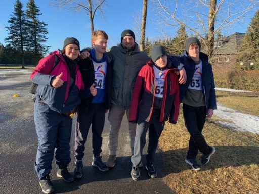 Gruppe von fünf Personen auf einer Straße, lächelnd und in sportlicher Kleidung.