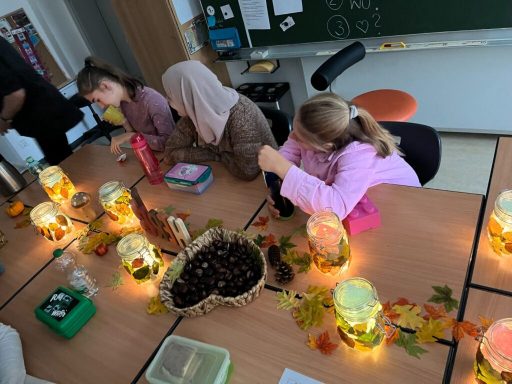 Kinder arbeiten an einem Tisch mit Laternen und herbstlicher Dekoration.
