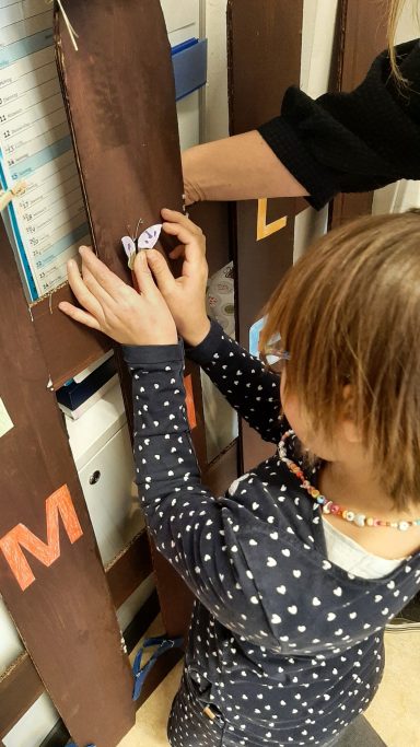 Ein Kind spielt an einer interaktiven Wand mit bunten Buchstaben.