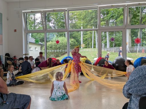 Kindershow in einem Raum mit bunten Tüchern und mehreren Kindern, die zuschauen.