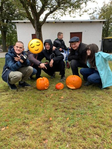 Fünf Personen posieren um verschiedene Kürbisse im Freien.