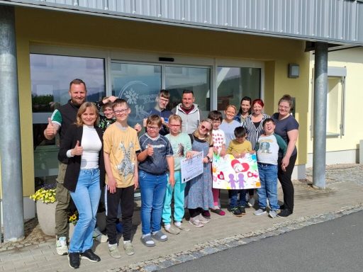 Gruppe von Kindern und Erwachsenen, die vor einem Gebäude posieren und lächeln.