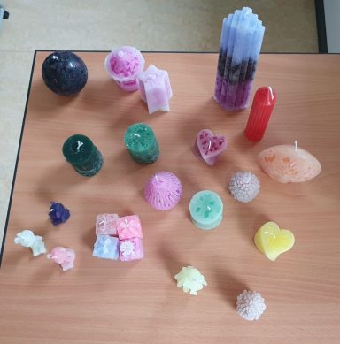 Verschiedene farbige Kerzen und Wachsskulpturen auf einem Tisch.