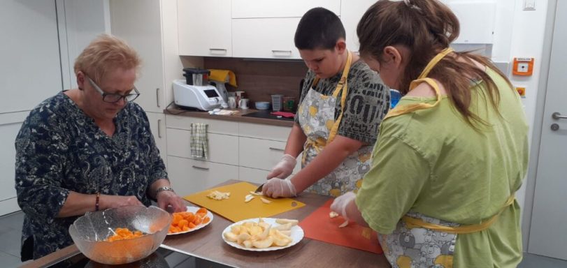 Drei Personen bereiten gemeinsam Essen in einer modernen Küche vor.