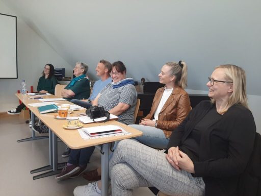 Sechs Personen sitzen an einem Tisch in einem Besprechungsraum.