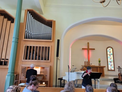 Ein Musiker am Klavier spielt neben einem Organ in einer Kirche.