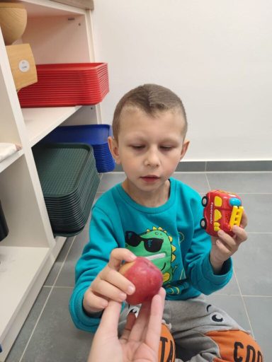 Ein Junge hält einen roten Ball und ein Spielzeug in der Hand.