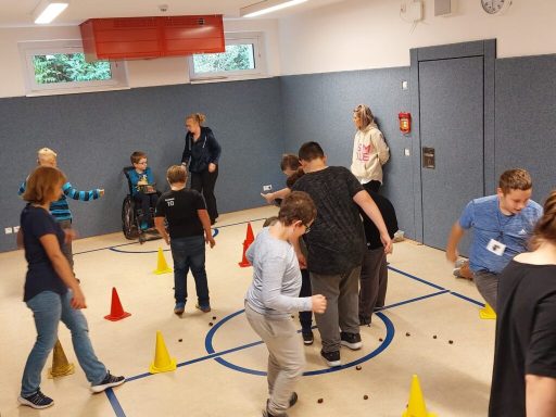 Kinder und Betreuer in einem Raum, der mit Kegel und Hindernissen für Aktivitäten gestaltet ist.