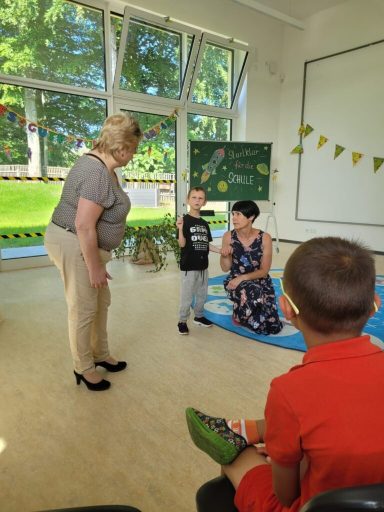 Eine Frau spricht mit einem Kind in einem hellen Raum mit Lernmaterialien.